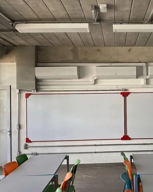 Sala de aula com unidade split instalada em altura sobre o quadro.