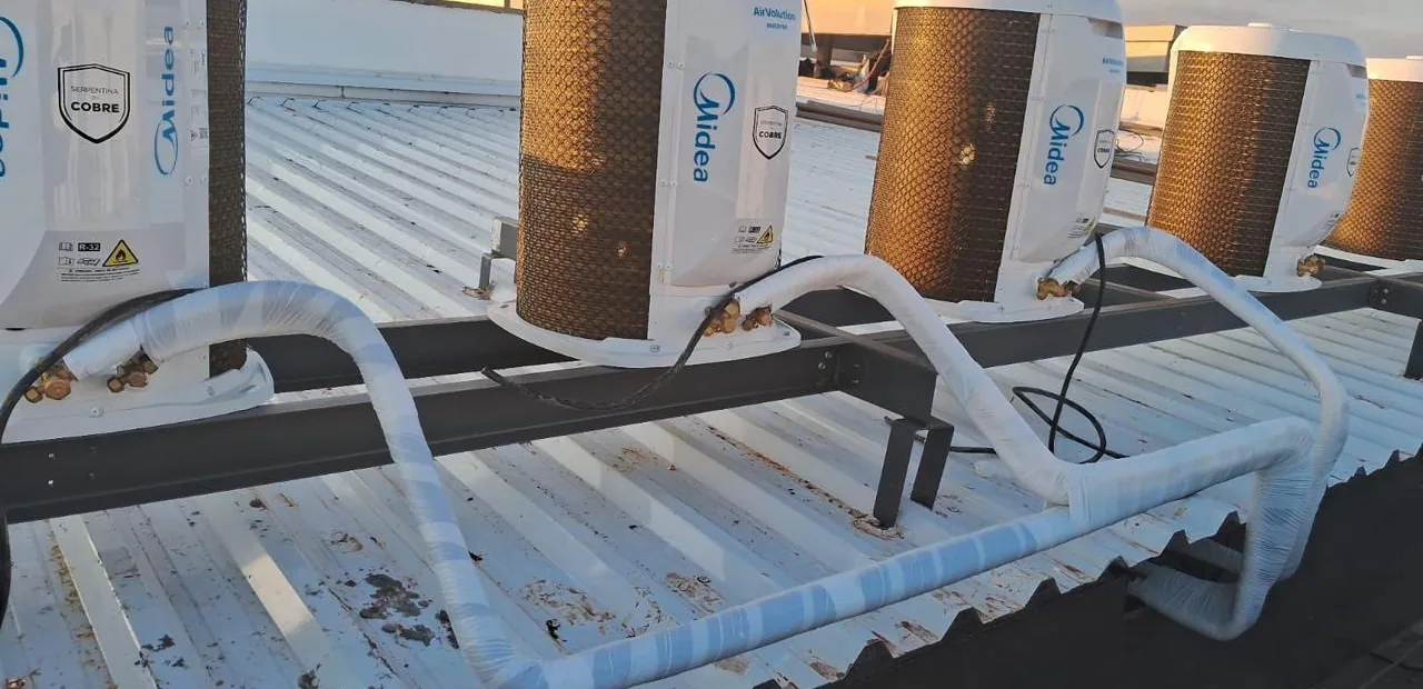 Bateria de condensadoras instaladas em cobertura industrial com tubulação frigorífica isolada.